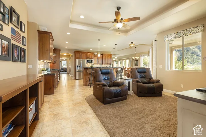 Open-concept living space featuring a tray ceiling, recessed lighting, and a ceiling fan