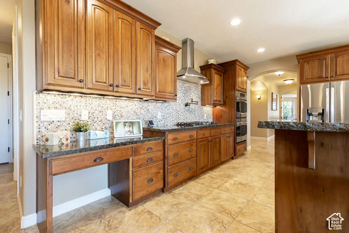 Wood-finish cabinetry, tile backsplash, stainless steel appliances, built-in double oven, and granite countertops