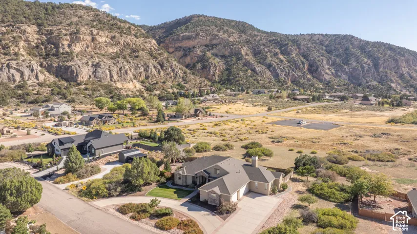 Stone and stucco exterior residence with a pitched roof, attached garage, and paved driveway, set against a mountainous backdrop