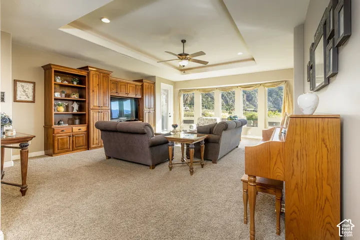 Built-in media center with shelving, tray ceiling with recessed lighting, ceiling fan, and large bay windows