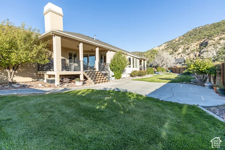 Stucco exterior with a covered patio, multiple glass sliding doors, and a concrete patio