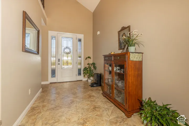 Entryway featuring a vaulted ceiling, decorative front door with sidelights, and patterned tile flooring