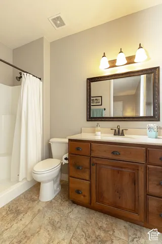 Wood-finish vanity with ample storage, light-toned countertop, and an ornate framed mirror