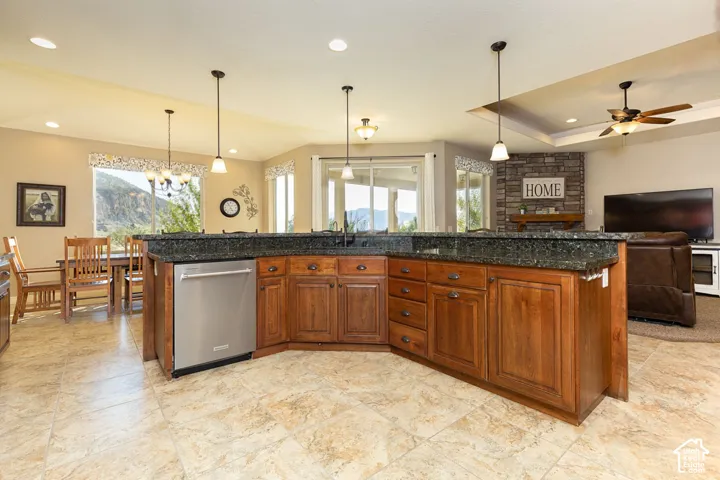 Spacious open-concept area featuring a kitchen island with dark countertops, wood cabinetry, and a stainless steel dishwasher