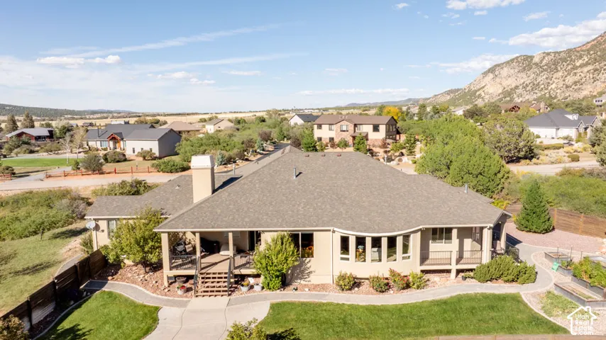 Expansive paved pathway with manicured lawn, multiple raised garden beds, and a covered porch