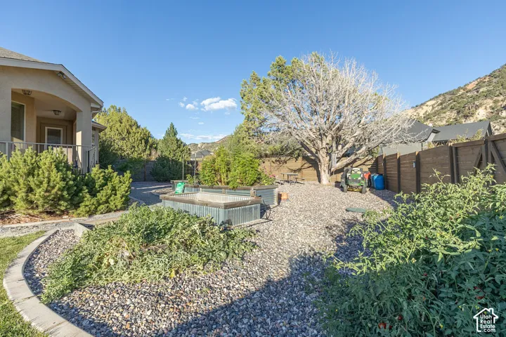 Landscaped backyard featuring raised garden beds, gravel ground cover, and a privacy fence