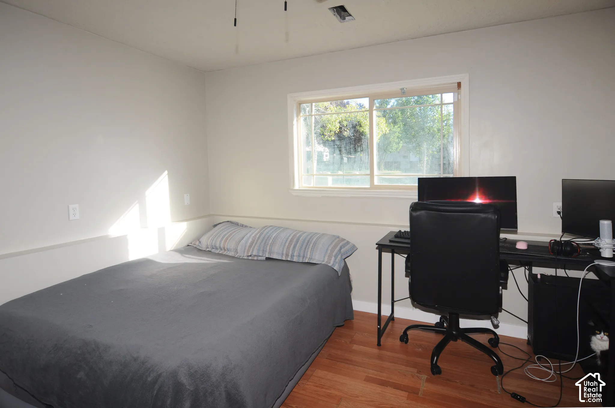 Wood-finish flooring, white walls, and a window with a light-colored frame
