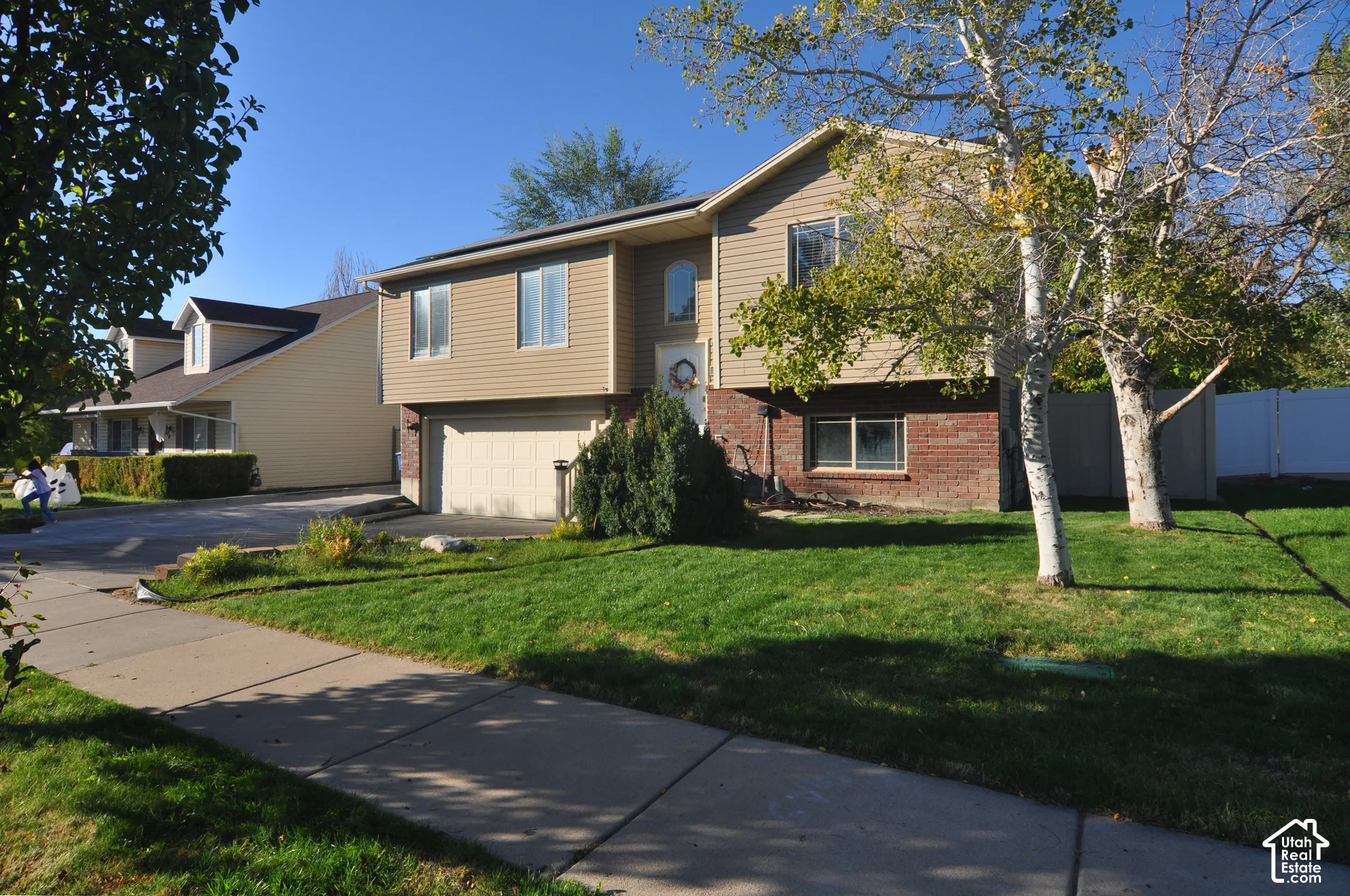 Two-story residence featuring tan siding and brick accents, an integrated single-car garage, and a concrete driveway