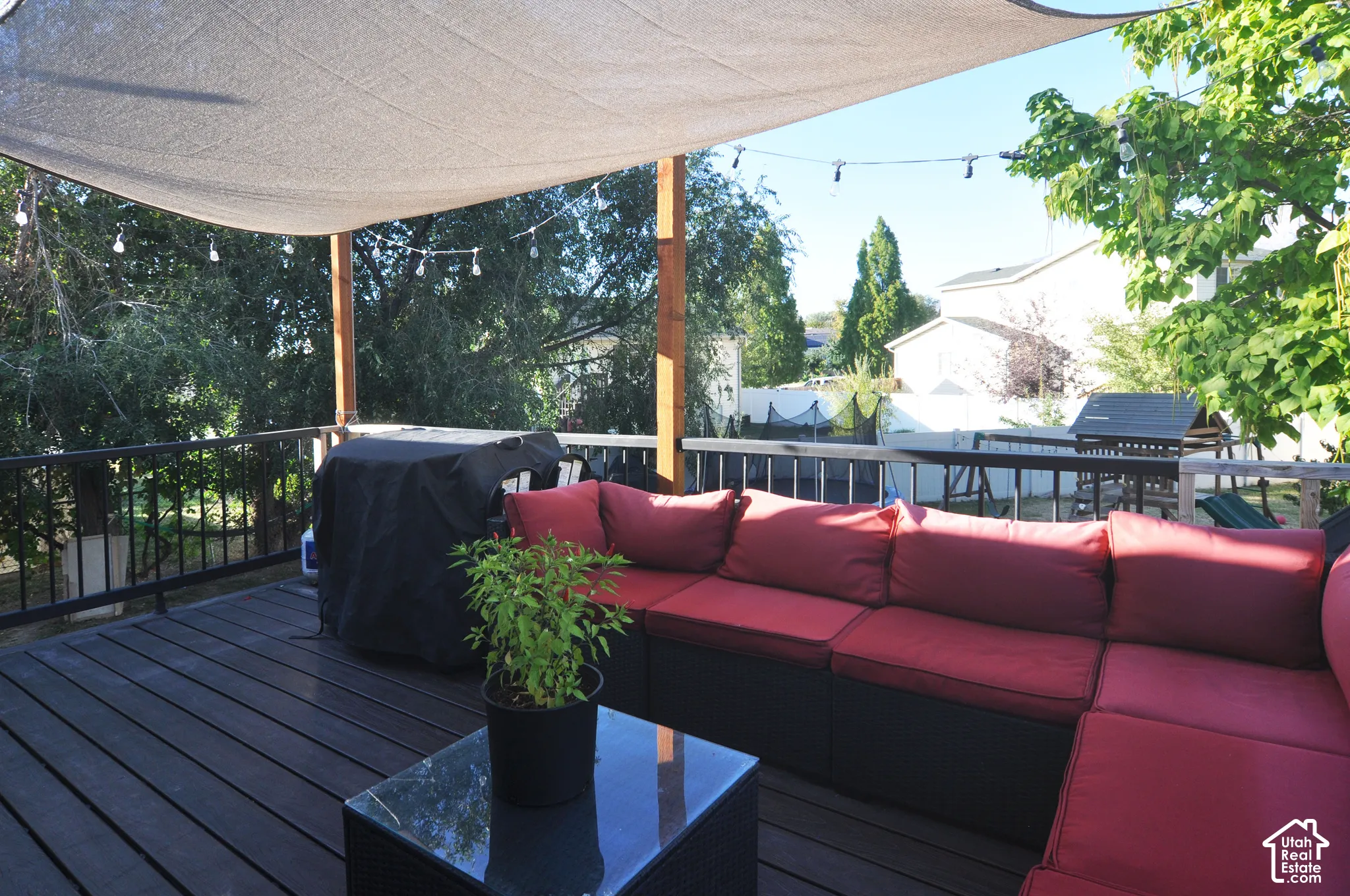 Expansive outdoor deck featuring dark-toned decking, black metal railings, and a large sunshade