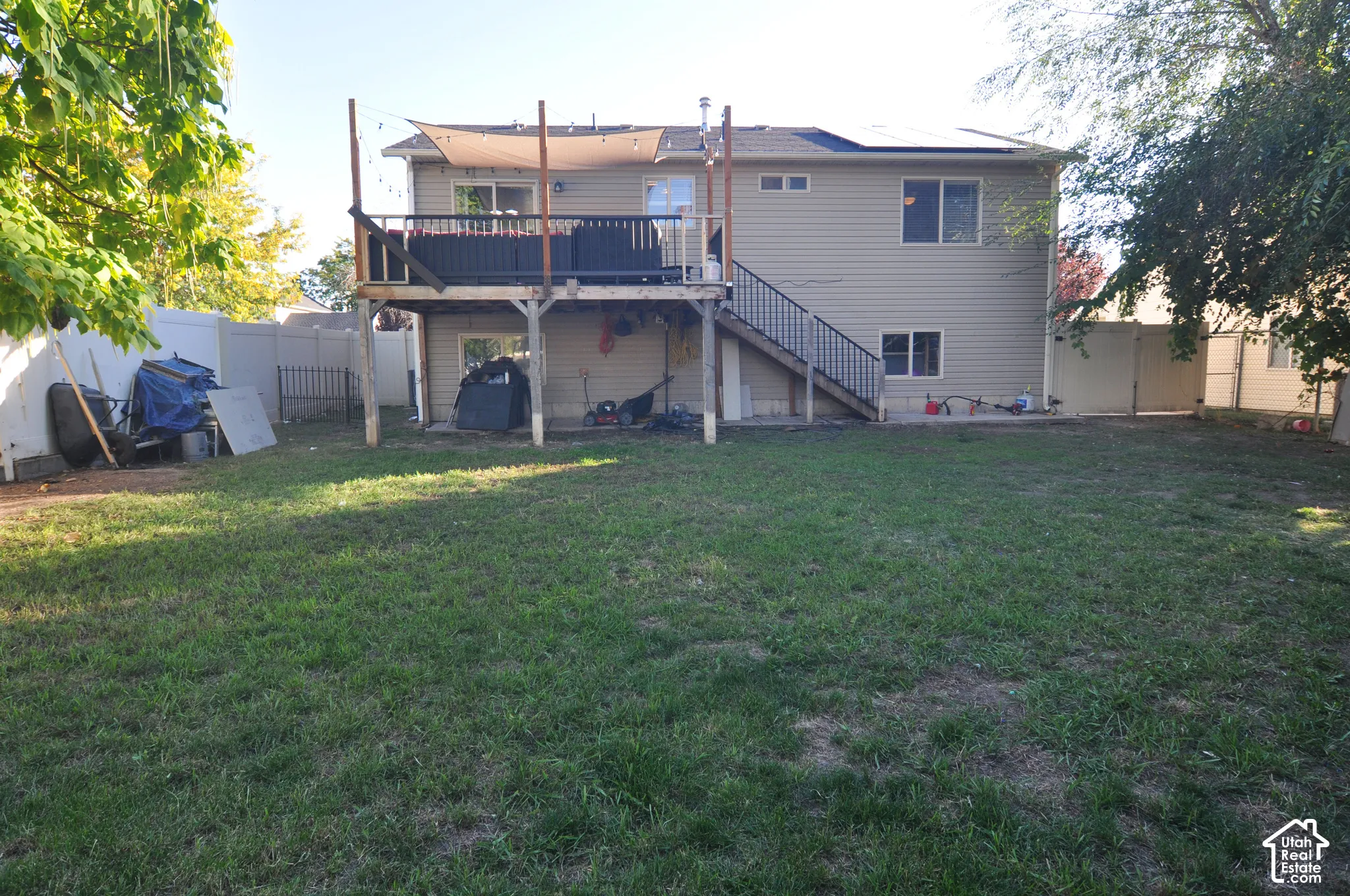 Expansive grassy yard with a two-story exterior featuring siding, an upper-level deck, and a lower-level concrete patio