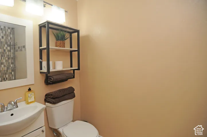 White vanity with a ceramic sink, chrome faucet, and overhead three-bulb vanity light