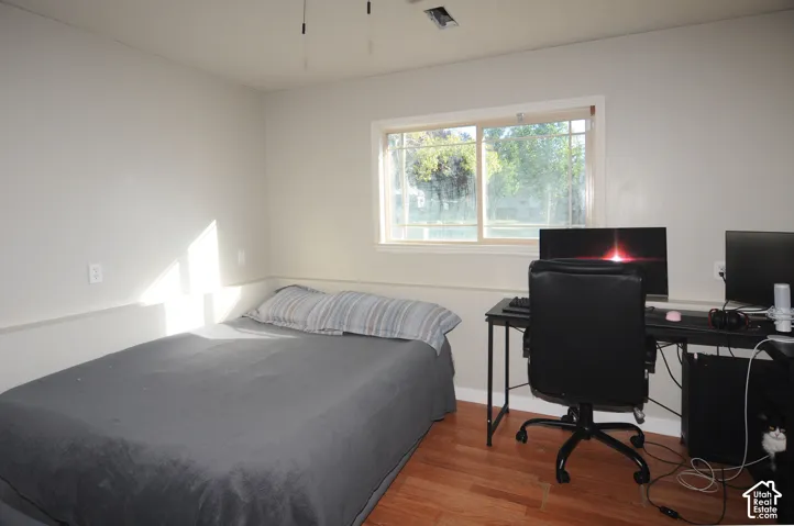 Wood-finish flooring, white walls, and a window with a light-colored frame