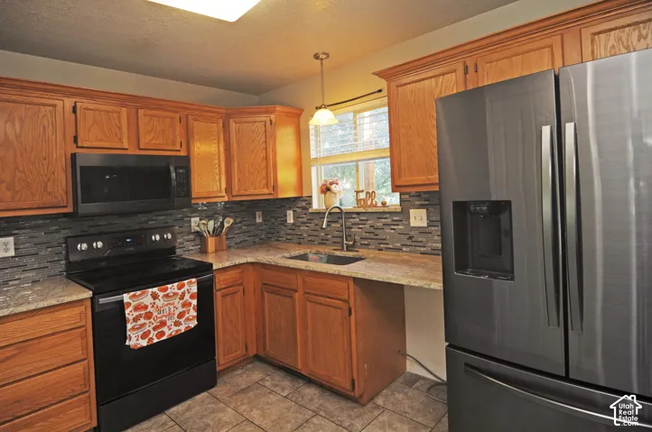 Oak cabinetry with crown molding, light-toned countertops, subway tile backsplash, stainless steel appliances, and tile flooring