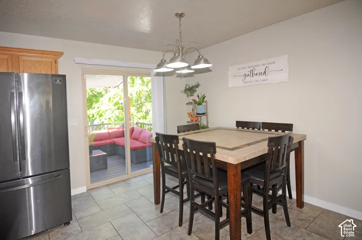 Stainless steel refrigerator, built-in wooden cabinetry, tile flooring, sliding glass door, and a multi-light fixture
