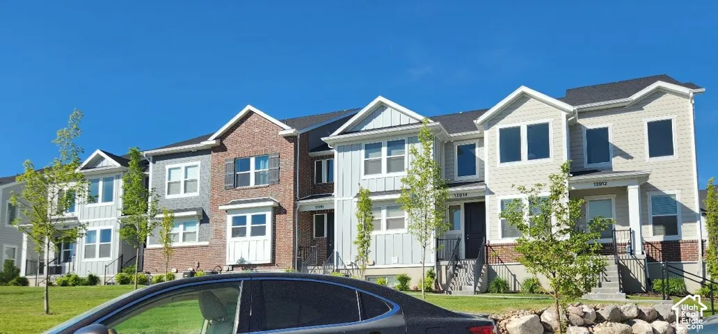 Row of multi-story residences featuring varied exterior finishes including brick, horizontal siding, and vertical board-and-batten accents
