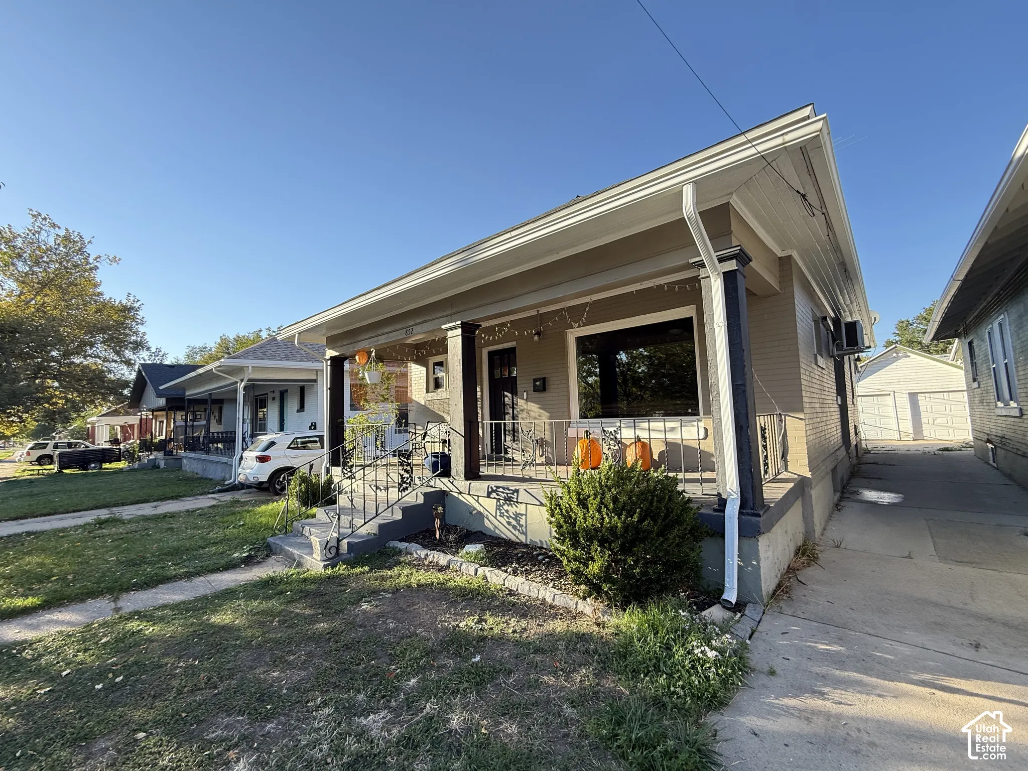 Brick exterior, covered front porch, concrete pathway, established landscaping, and a side-yard concrete driveway