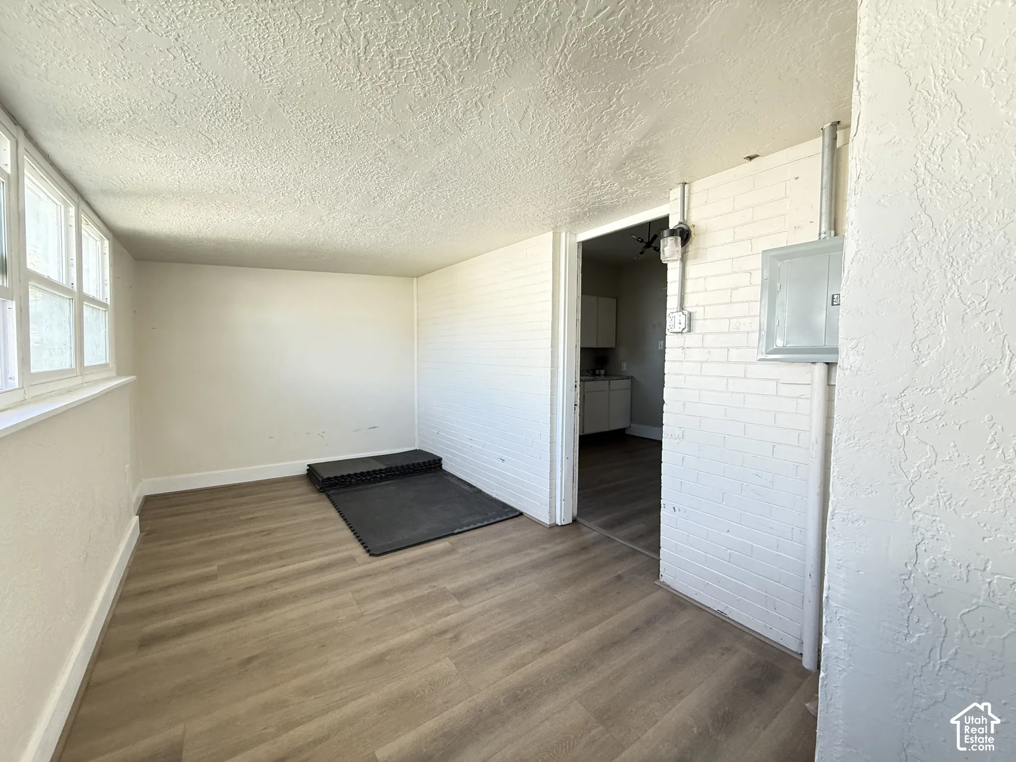Wood-finish flooring, white-painted brick wall, and multi-pane windows