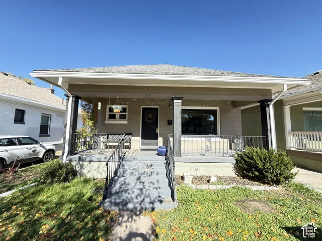 Single-story exterior featuring a covered front porch, decorative metal railings, substantial support pillars, and stone-accented facade