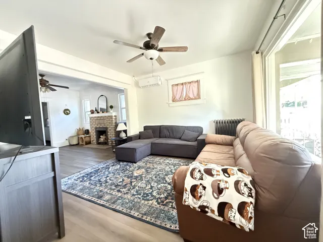 Warm wood-finish flooring, a ceiling fan with integrated lighting, and a white interior wall finish