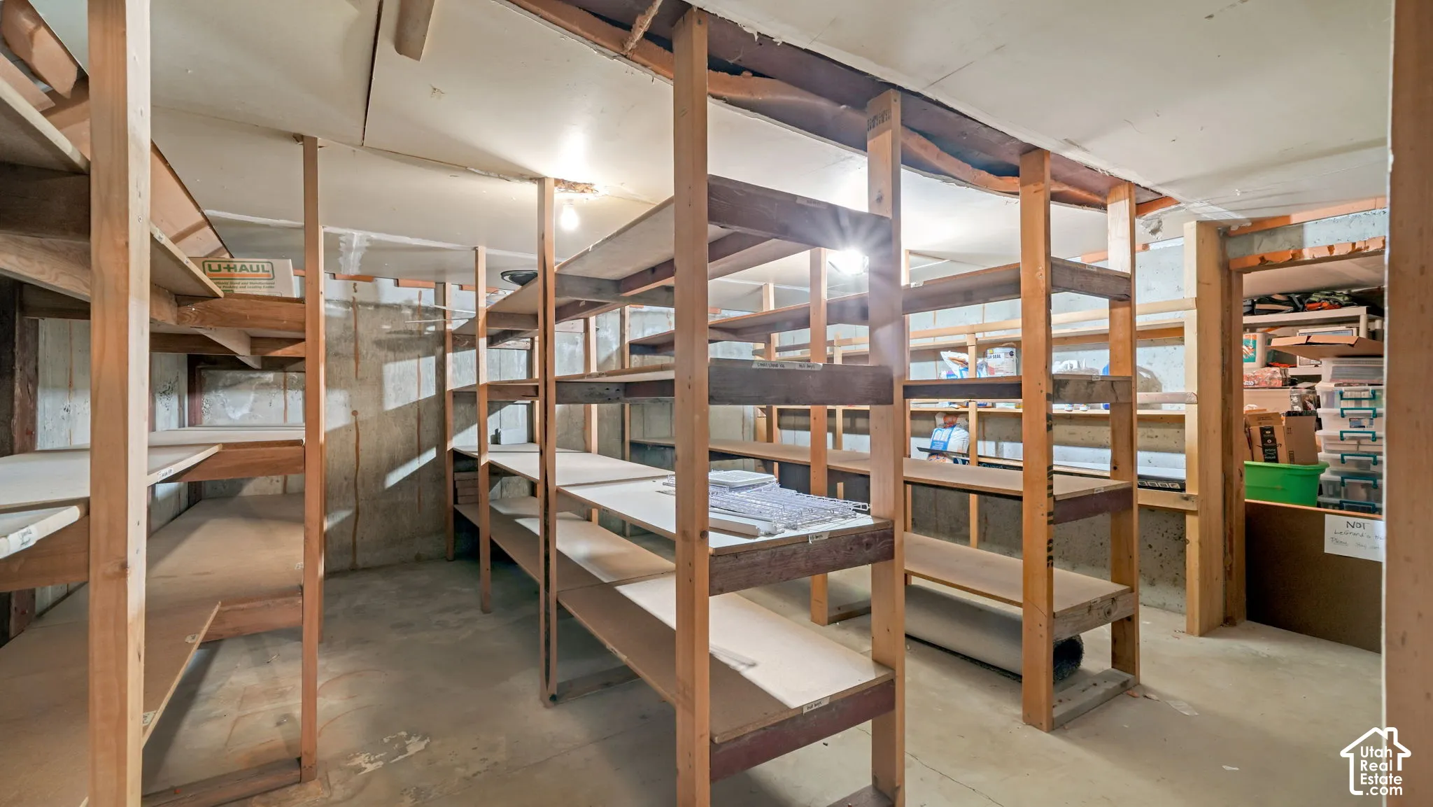 Extensive wood shelving system with multiple tiers, concrete flooring, and exposed ceiling joists