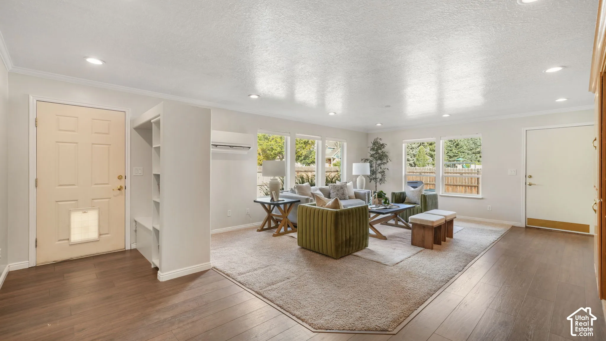 Open-concept living area with wood-finish flooring, recessed lighting, and multiple windows