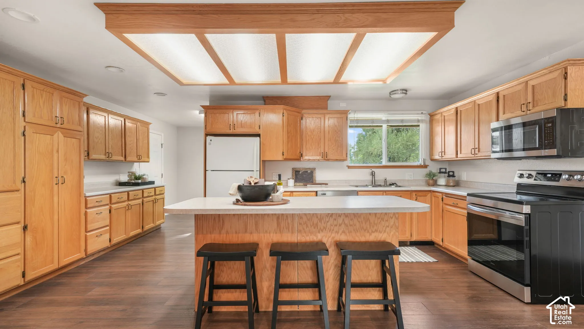 Kitchen featuring wood-finish flooring, abundant cabinetry, a central island with countertop seating, and stainless steel appliances