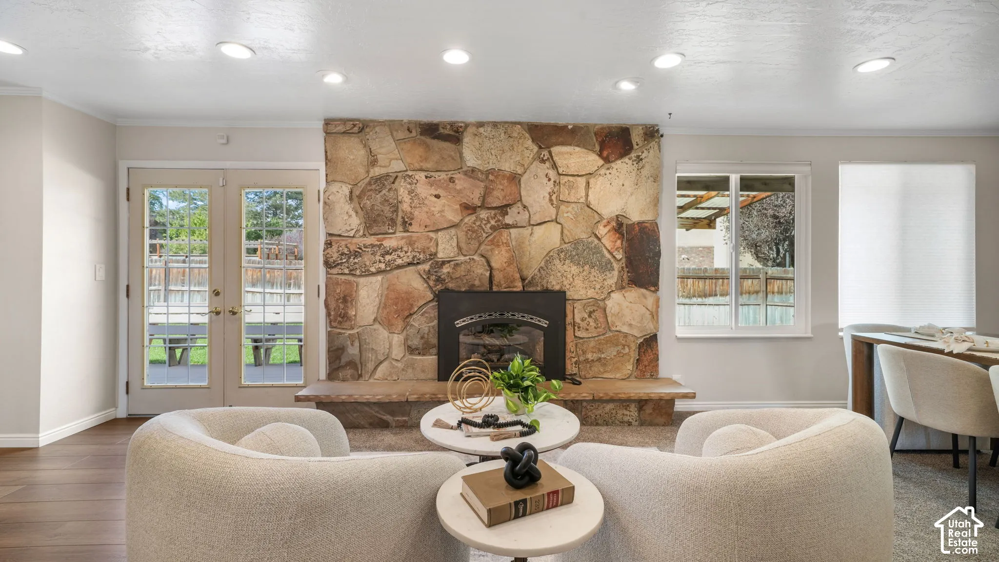 Stone fireplace with hearth, recessed lighting, wood-finish flooring, and double glass-paneled doors