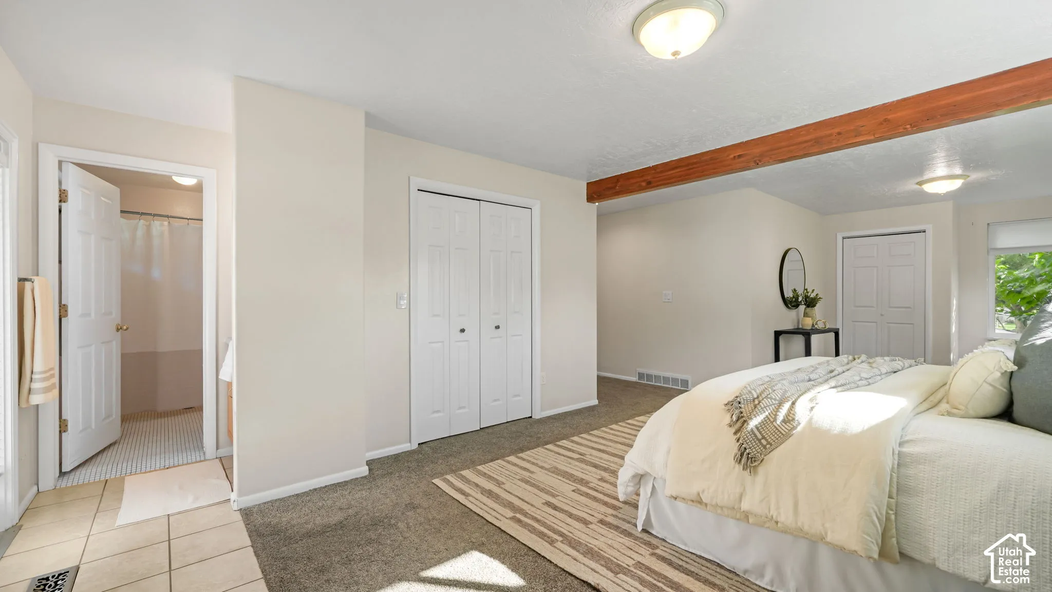 Carpeted flooring, exposed wood ceiling beam, white bi-fold closet doors, recessed ceiling lighting, and a neutral wall color