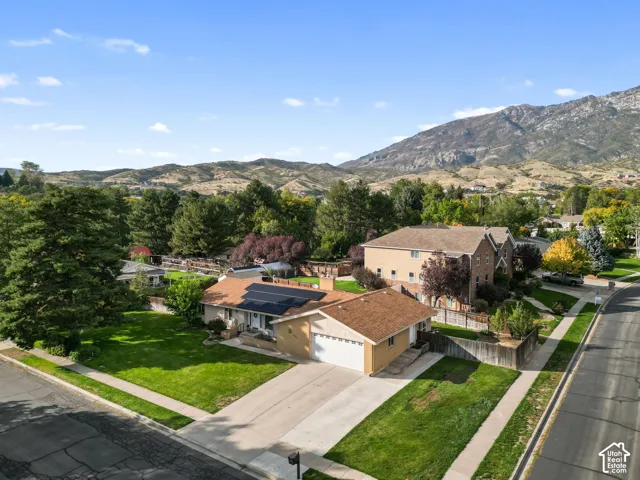 Rambler residence with an attached garage, solar panels, and a concrete driveway