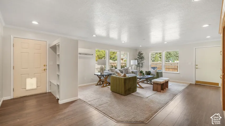 Open-concept living area with wood-finish flooring, recessed lighting, and multiple windows