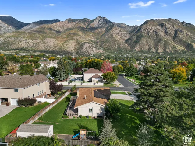 Mountain backdrop framing the neighborhood, mature trees, residential street, and manicured lawns