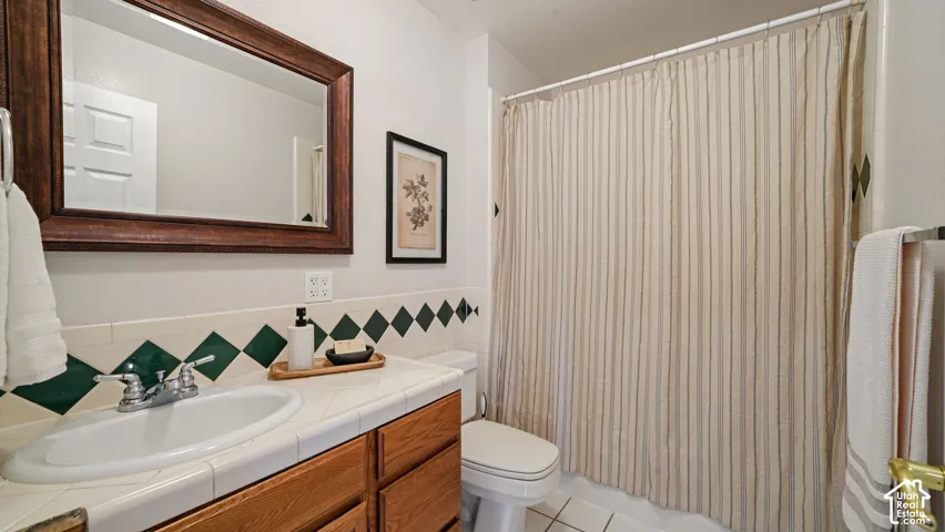 Hardwood vanity with a drop-in sink, chrome faucet, tiled countertop, and wood-framed mirror