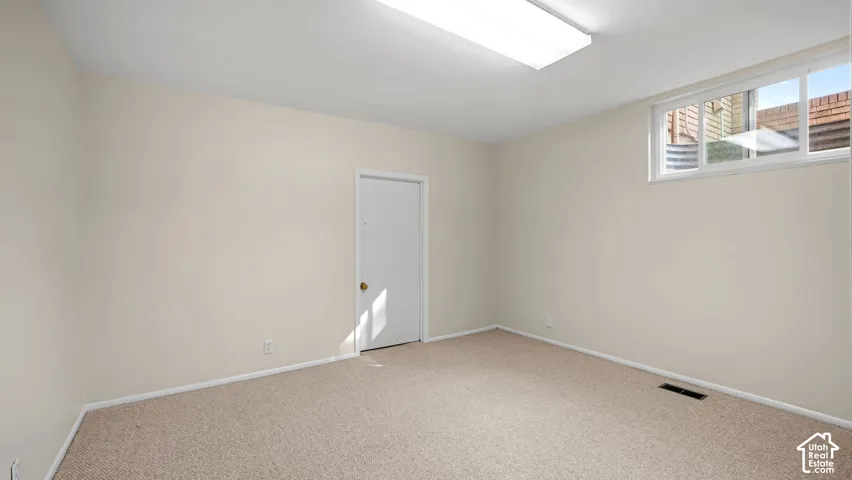 Bright room featuring neutral-toned carpet, a window, and overhead fluorescent lighting
