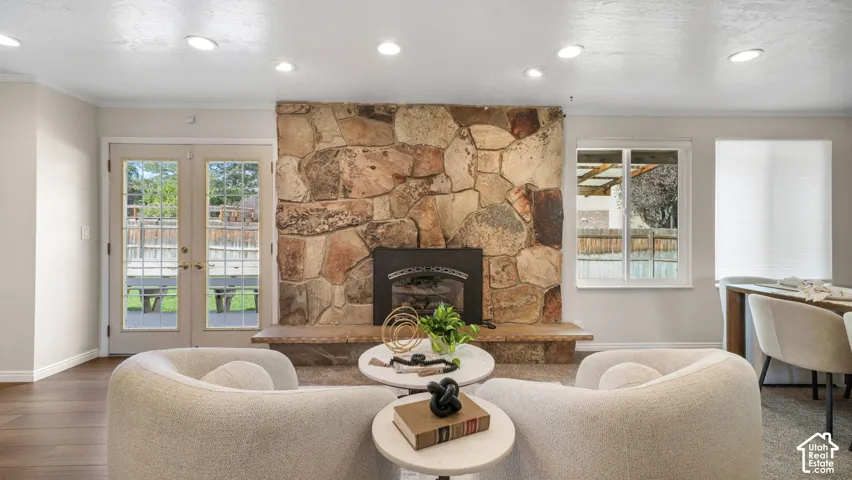 Stone fireplace with hearth, recessed lighting, wood-finish flooring, and double glass-paneled doors