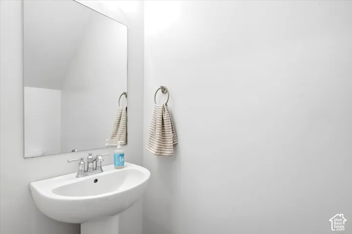 Pedestal sink with chrome faucet, wall-mounted mirror, and towel ring