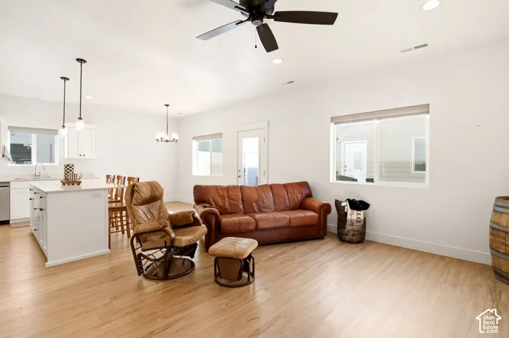 Open-concept floor plan featuring wood-finish flooring, a kitchen island with stone countertop, recessed lighting, and a ceiling fan