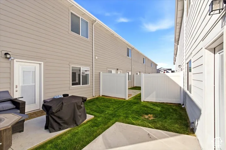 Private fenced yard with concrete patio, manicured lawn, and vinyl siding exterior