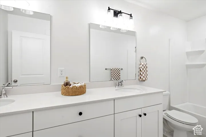 Dual vanity with white cabinetry, polished chrome fixtures, and a white countertop