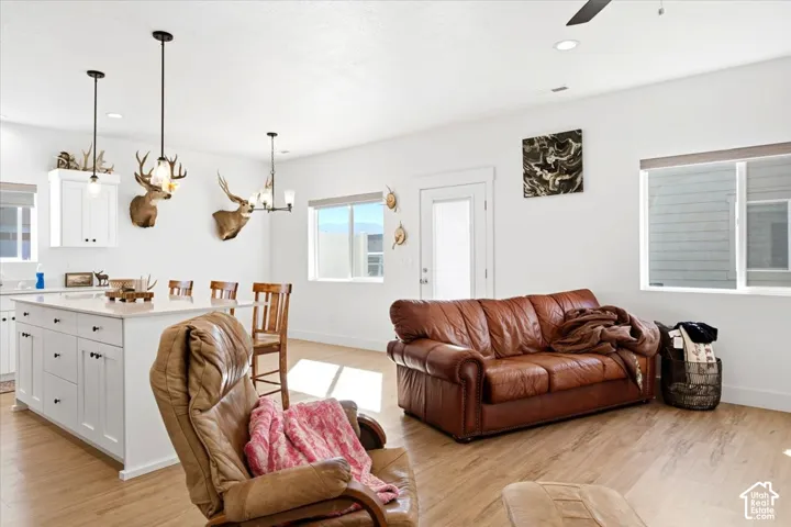 Open-concept living space featuring wood-finish flooring, white walls, recessed lighting, and a ceiling fan