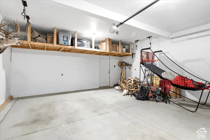 Garage with concrete flooring, overhead wooden shelving, and a white ceiling