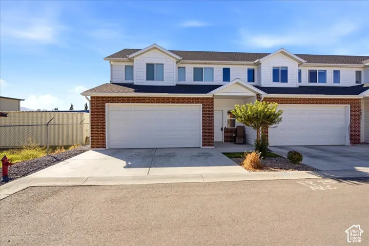 Brick and siding exterior with a two-car garage, concrete driveway, and a covered entry