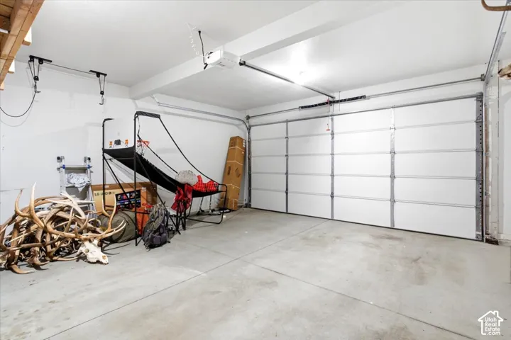 Garage with concrete flooring, white walls, and an automatic garage door opener