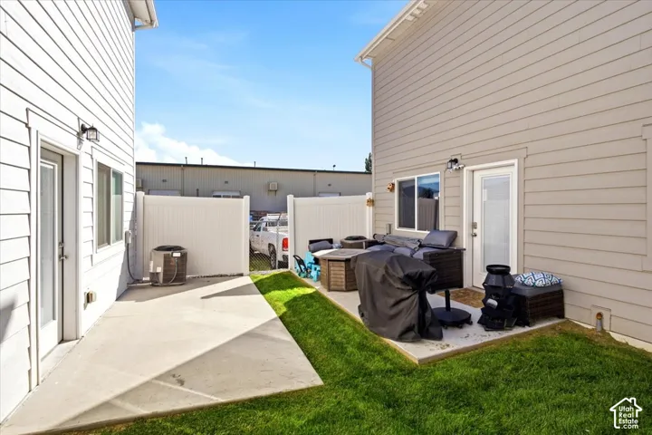 Private patio with concrete surfacing, white vinyl fencing, and a manicured lawn area