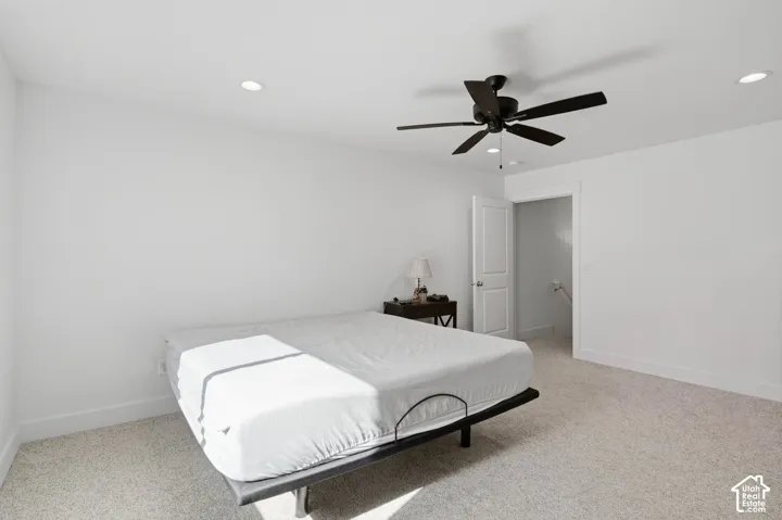Neutral-toned interior space featuring recessed ceiling lighting, a matte black multi-blade ceiling fan, and wall-to-wall carpeting