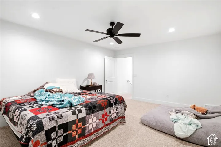 Recessed lighting, ceiling fan, white walls, carpeted flooring, and a white interior door
