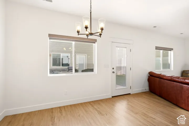 Wood-finish flooring, metal multi-light chandelier, sliding glass exterior door, and dual picture windows