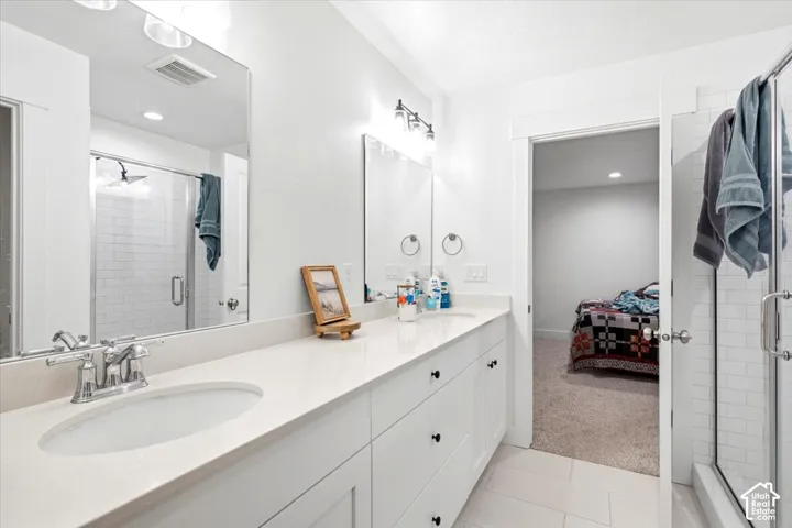 Double vanity with undermount sinks, light-toned countertop, and white cabinetry