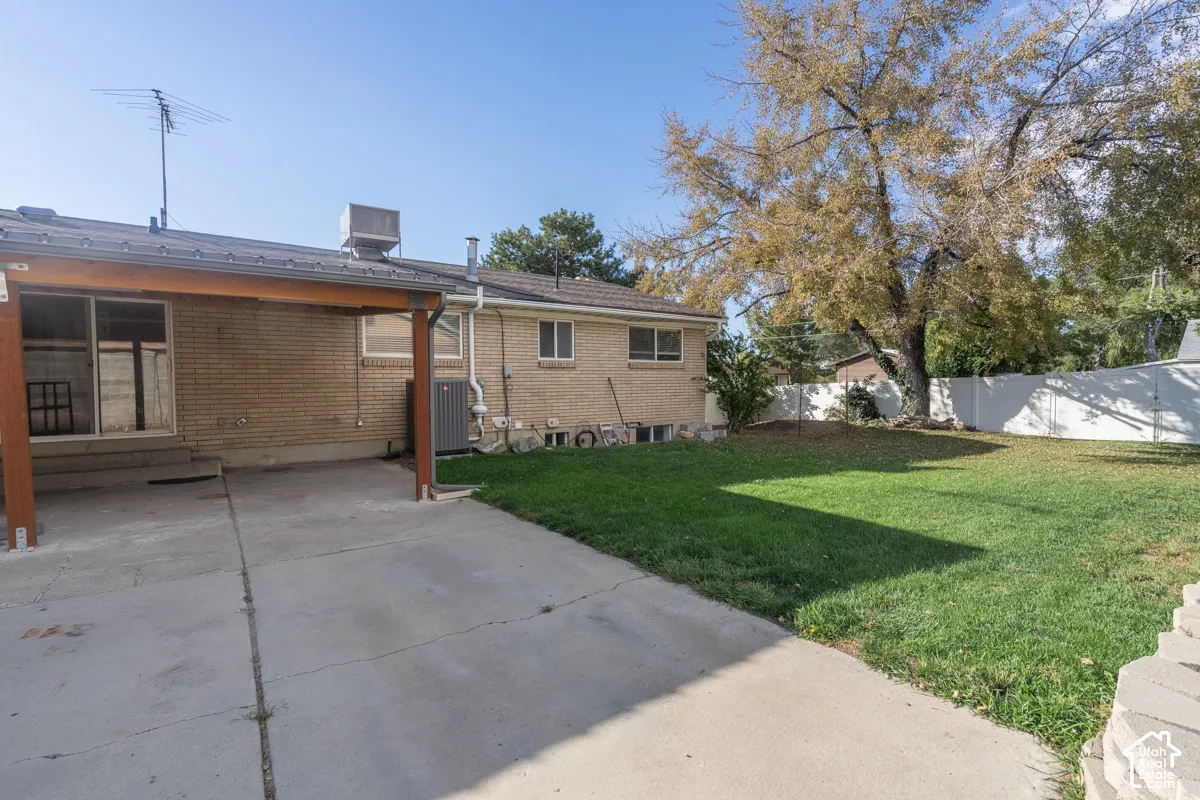 Brick exterior with covered patio, concrete patio, concrete pathways, and a grassy lawn