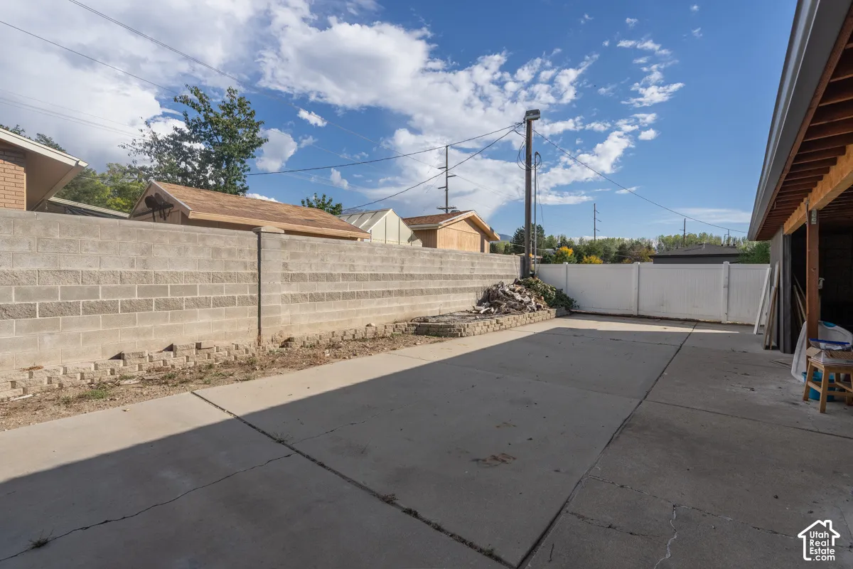 Paved concrete surface with a concrete block retaining wall and a white privacy fence
