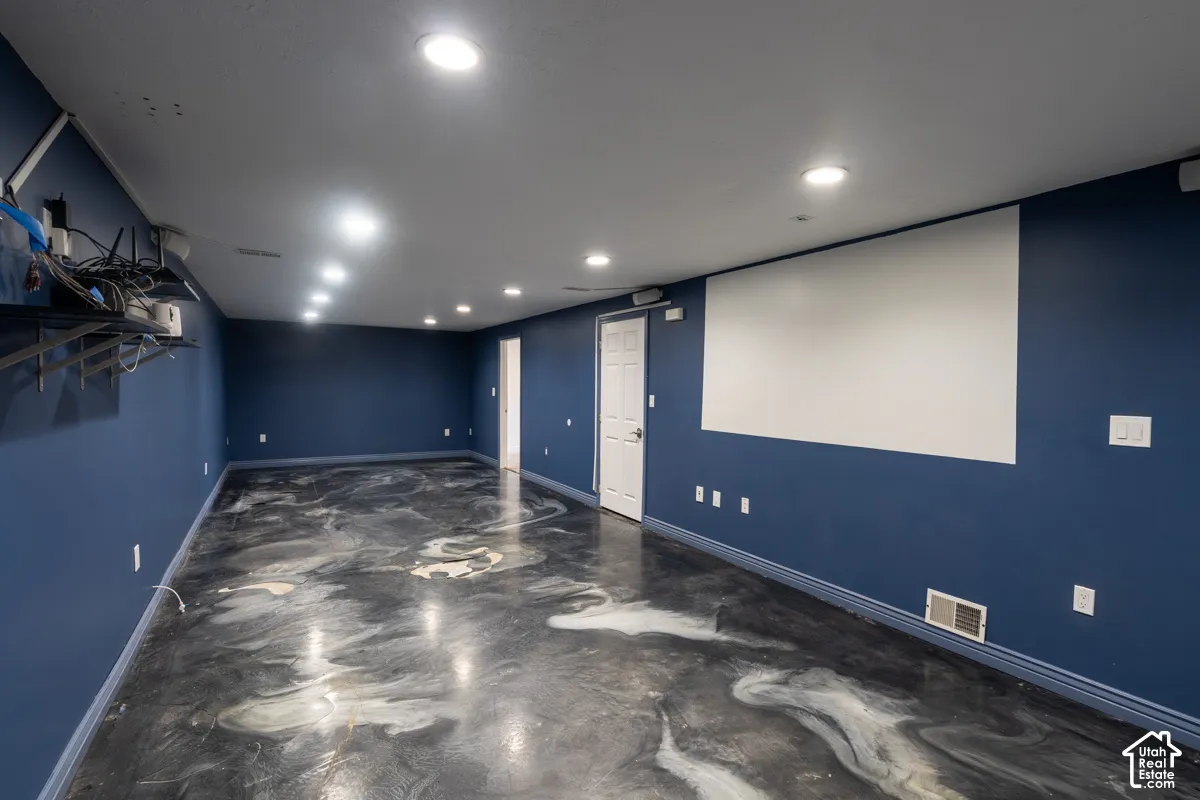 Spacious room featuring a projector screen, recessed lighting, and a unique marled epoxy floor
